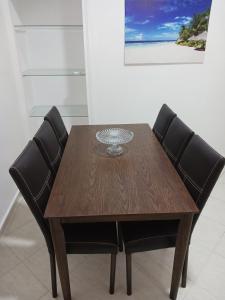 ein Holztisch mit vier schwarzen Stühlen um ihn herum in der Unterkunft Bijoux Harhoura in El Harhoura