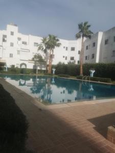 a swimming pool in front of a building with palm trees at Bijoux Harhoura in El Harhoura