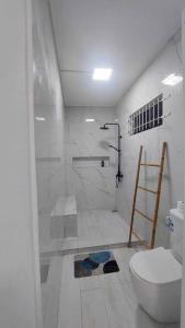 a white bathroom with a toilet and a shower at White Bliss in Terre Rouge