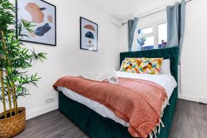 a bedroom with a green bed and a plant at Deluxe Apartment - 1 Min Away From Camden Market and Station in London