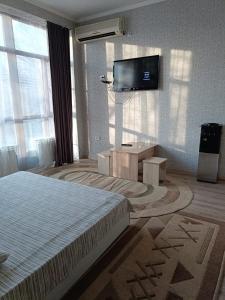 a bedroom with a bed and a flat screen tv at Ровный in Almaty