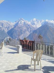 two chairs on a deck with mountains in the background at Aarav Homestay in Kalpa