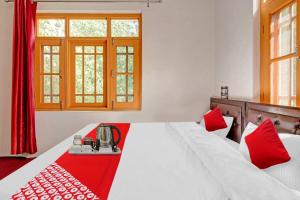 a bedroom with a large white bed with red accents at OYO Green Resort in Gandbal