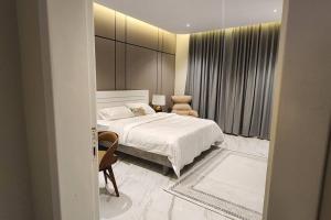 شقة مودرن بحي حطين 9 في الرياض: غرفة نوم بسرير ابيض وكرسي