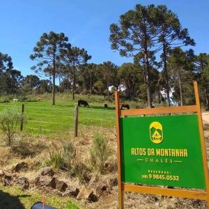 a green sign in a field with animals in the background at Chalés Altos Da Montanha - Mont Blanc in Bom Jardim da Serra