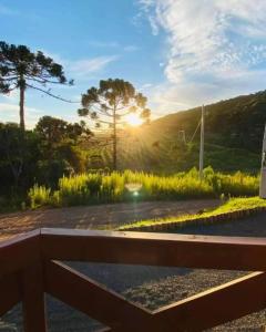a bench in a park with the sunset in the background at Chalés Altos Da Montanha - Mont Blanc in Bom Jardim da Serra