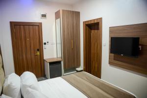 a hotel room with a bed and a flat screen tv at The Kingsley - La Prima Casa in Lagos