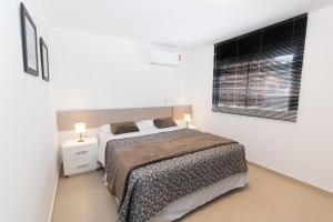 a white bedroom with a bed and a window at Morada Clariana in Curitiba