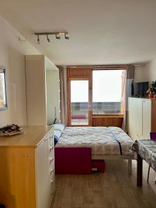 a bedroom with a bed and a desk and a window at Residence Ciel Bleu - Fraz Pos in Aosta