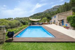 a swimming pool with a wooden deck and a house at Villa Can Ros in Capdellá