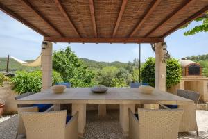a wooden table and chairs under a wooden pergola at Villa Can Ros in Capdellá