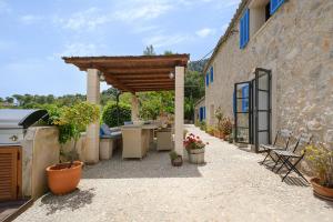 a patio with a wooden pergola next to a building at Villa Can Ros in Capdellá