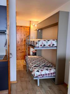 a bedroom with two bunk beds and a kitchen at Residence Ciel Bleu - Fraz Pos in Aosta