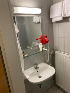 a bathroom with a white sink and a red phone at Hotel Restaurant Zum Wendelwirt in Germaringen