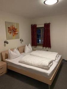 a bedroom with a large bed with white sheets at Hotel Restaurant Zum Wendelwirt in Germaringen