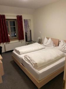 a bedroom with a bed with white sheets and a window at Hotel Restaurant Zum Wendelwirt in Germaringen