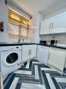 a white kitchen with a washer and dryer in it at Deluxe Apartment - Next to Kings Cross - Eurostar & Euston Station in London