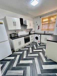 una cucina con armadietti bianchi e pavimento a scacchi di Deluxe Apartment - Next to Kings Cross - Eurostar & Euston Station a Londra