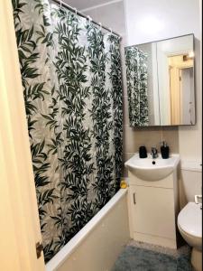 a bathroom with a black and white shower curtain and a sink at Peaceful flat in Central London in London