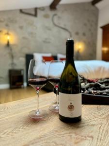 eine Flasche Wein und zwei Gläser auf dem Tisch in der Unterkunft Pax et Amor Chambres d'hôtes de charme - Charming B&B in Mazerolles-du-Razès