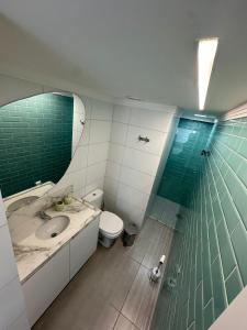 a bathroom with a sink and a toilet and a mirror at SUNNY HALL, FLAT COM TRÊS QUARTOS in Porto De Galinhas