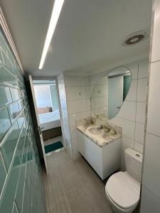 a bathroom with a toilet and a sink and a mirror at SUNNY HALL, FLAT COM TRÊS QUARTOS in Porto De Galinhas