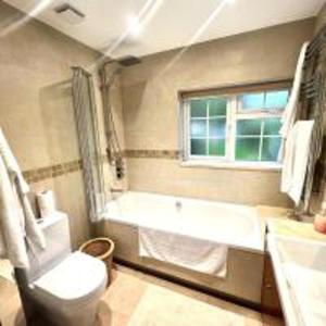 uma casa de banho com uma banheira, um WC e uma janela. em Inviting 4-Bed House in Finchley London em Hendon