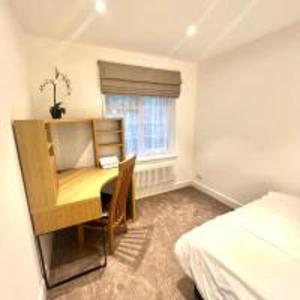 Schlafzimmer mit einem Schreibtisch, einem Bett, einem Schreibtisch und einem Fenster in der Unterkunft Inviting 4-Bed House in Finchley London in Hendon