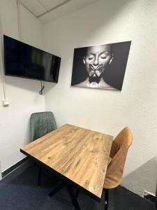 uma mesa de madeira com duas cadeiras e uma televisão na parede em Pension Bavaria Immobilien em Nurembergue
