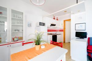 a kitchen with white cabinets and a table with a plant at Appartamento a 20mt dal mare con piscina condominiale in Marcelli