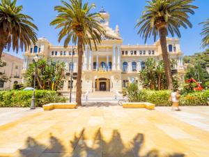 a large building with palm trees in front of it at Cubo's Apartamento 33 Carreteria 3B in Málaga