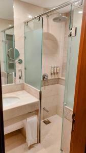 y baño con lavabo y ducha acristalada. en Quetta Serena Hotel en Quetta