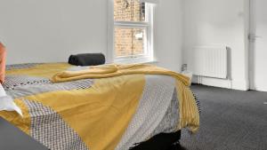 a bedroom with a bed with a yellow blanket on it at 4 Bed 2 Bath House with Private Garden in London