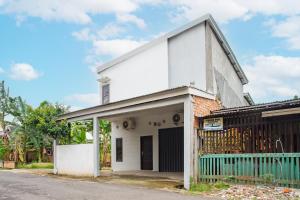 una casa blanca con una valla azul en una calle en OYO 93476 Owo Guest House Syariah, en Jambi