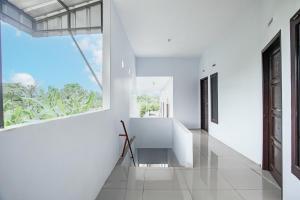Habitación con paredes blancas y ventana grande. en OYO 93476 Owo Guest House Syariah, en Jambi