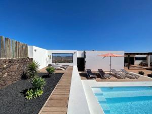 a pool with chairs and an umbrella next to a building at Villa with views and Villaverde in Villaverde