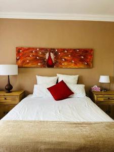 a bedroom with a white bed with a painting on the wall at 21 at Melody in Hartbeespoort