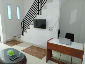 sala de estar con escalera y mesa con ordenador portátil en OYO 93476 Owo Guest House Syariah, en Jambi