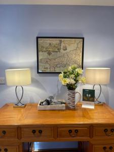 a desk with two lamps and a map on the wall at Cobble Cottage in St Just