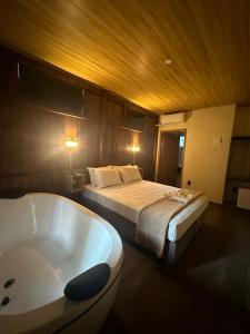 a bedroom with a bed and a bath tub at Pousada Ponta da Vigia in Penha