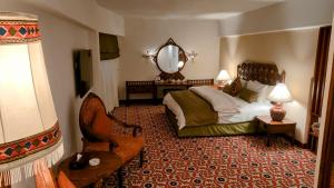 Quetta Serena Hotel في كويتا: غرفة نوم بسرير ومرآة وكرسي