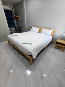 een slaapkamer met een bed met witte lakens en een tafel bij ลีลาโคซี่ รีสอร์ท ณ สิชล in Sichon