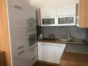 una pequeña cocina con armarios blancos y fregadero en Apartmán v centre, 4os., parking, en Bratislava