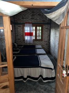 a bedroom with three beds in a brick wall at HOTEL FAZENDA Engenho Velho in Ubajara