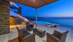 a patio with a table and chairs and a swimming pool at Luxury seafront design villa Kyma in Tersanas Owner listing in Tersanas +28 photos