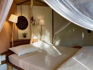 1 dormitorio con 1 cama blanca con dosel en Bakuba Lodge - Le petit hôtel du Voyageur, en Ankilibe