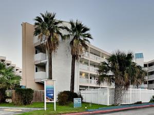 um grande edifício de apartamentos com palmeiras em frente em Villa Del Sol 1145 - Mermaids Hideaway em Corpus Christi