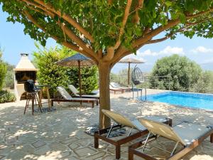 un grupo de sillas y un árbol junto a una piscina en Villa Taf - Kreta, en Kamilari