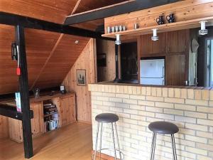 a kitchen with two stools in front of a brick bar at Cozy Holiday cottage at Ringkøbing Fjord in Hemmet +25 photos