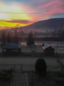 einen Sonnenuntergang über einem Feld mit einem Zaun und einer Scheune in der Unterkunft Shum Cheremosha in Werchowyna